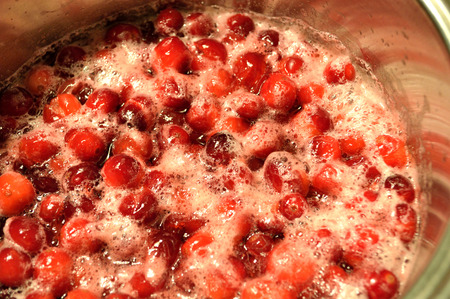 Bright red cranberries cooking in a pot on stove, to make whole-berry cranberry sauce.の写真素材