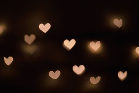 Bokeh lights, in the shape of little hearts, against black backgroundの写真素材