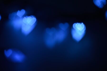 Bokeh lights, in the shape of little hearts, bright blue clusters of hearts against black backgroundの写真素材