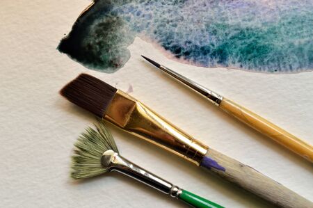 Wet on wet technique example of a fluid watercolor wash on watercolor paper with 3 paintbrushesの写真素材