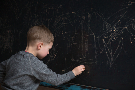 Back view of male elementary school student writes on the Blackboardの写真素材