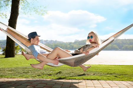 Contented couple relaxing in a hammock On grass and blue sky backgroundの写真素材