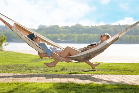 Contented couple relaxing in a hammock On grass and blue sky backgroundの写真素材