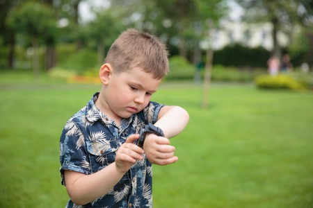 little boy looking at watch on his handの写真素材