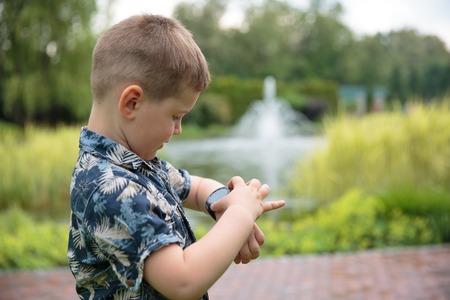 little boy looking at watch on his handの写真素材