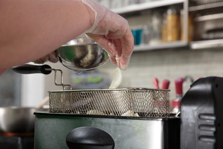 The pieces of Onions are thrown into a deep fryerの写真素材