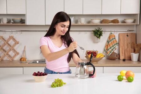 Woman pouring tea into the kettle on the kitchenの写真素材