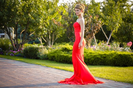 Young pretty woman in red dress in the park in sun dayの写真素材