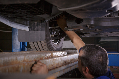Mechanic Works on a Car. Repairs chassisの写真素材
