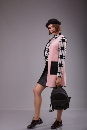 Portrait of extraordinary woman dressed in black hat and plaid shirt staying over gray background. Studio shootの写真素材