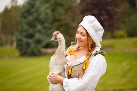 a peasant woman with a goose in her arms amid a meadow. fairy taleの写真素材