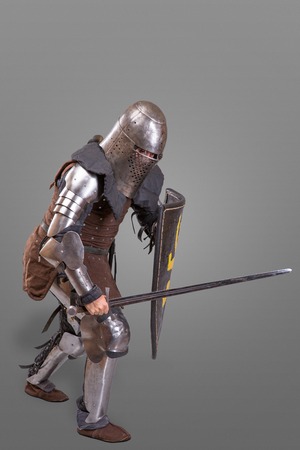 knight in breaths in a helmet with a sword and shield in battle isolated over grey backgroundの写真素材