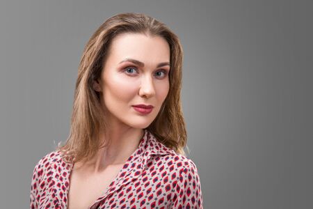 Portrait of a smiling middle aged caucasian woman isolated against grey background.の写真素材