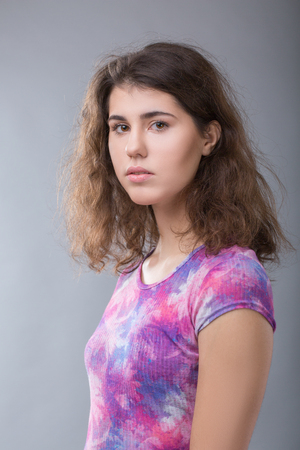 Portrait of an ordinary young brunette woman on gray backgroundの写真素材
