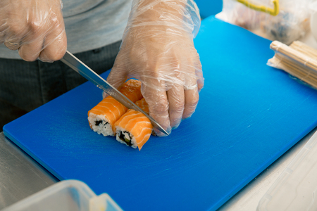 hand cuts the roll closeup on a cutting board. the chef prepares sushi at a Japanese restaurant. cookeryの写真素材