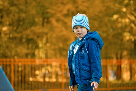cute baby boy standing in autumn parkの写真素材