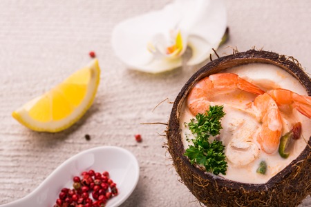 Tasty Shrimp soup with coconut milk, kaffir lime leaves, galangal, chilli and lemon grass in a coconut. decor of orchidの写真素材