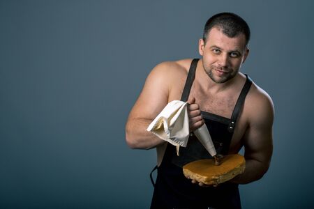 Confectioner is decorating chocolate cake. chef chewing chocolate cream on cake on dark background