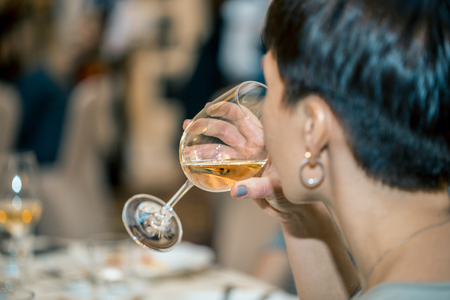 woman drinking white wine at an official reception in a restaurantの写真素材
