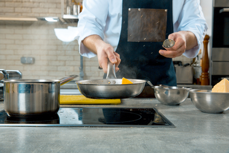 Mid section of chef preparing food in the kitchen of a restaurant. the chef fry food in a frying panの写真素材