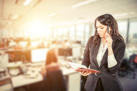 young business woman holding notepad and talking on mobile phoneの写真素材