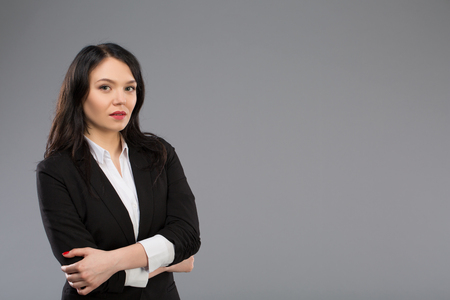 Standing businesswoman portrait on grey background and looking at cameraの写真素材