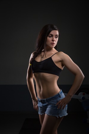 Portrait of attractive woman with muscular body. standing on dark background. Fit and sexy young female bodybuilder posing. Halthy conceptの写真素材