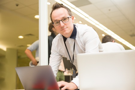man with glasses typing on laptop at the presentation