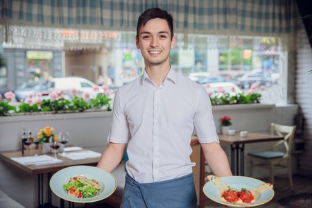 Waiter carrying plates with dish on some festive event, party or wedding receptionの写真素材