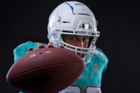 Agressive American football sportsman player on black background running in action. Sport wallpaper with copyspace.の写真素材