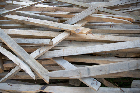 Chaotic pile of used wooden boards with nails. Background. dump