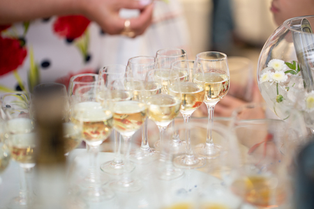Table top full of glasses of sparkling white wine or champagne. Spread of alcoholic beverages for celebration toasting at wedding reception.の写真素材