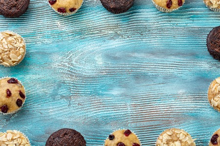 Homemade chocolate chip muffins as a frame on blue wooden table. Copy spaceの写真素材
