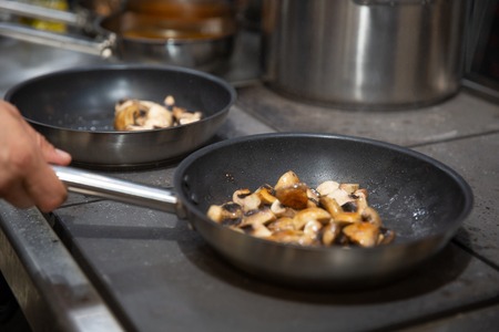 chef cooking stir fry mushroom sliced in pan at a restaurant, stir fry vegetables in the wok, professional chef cooking mealの写真素材