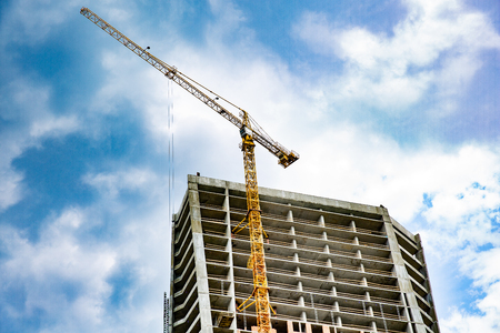 Skyscraper construction. Tower crane over construction building on sky background