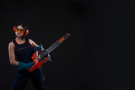 young woman with motor saw or chainsaw on a black background. gender equality. Copy space