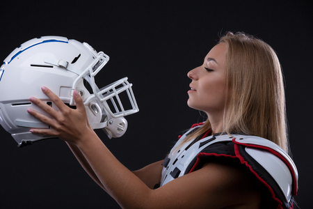 Attractive female american football player in uniform posing with helmet. girl sportswoman. Gender equalityの写真素材