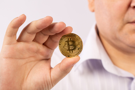 Golden Bitcoin in a man hand, Digitall symbol of a new virtual currency on white backgroundの写真素材