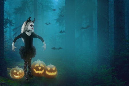 Halloween, holidays, masquerade concept - the portrait of young little beautiful girl with skull makeup on pumpkins background. Halloween, face-art, skull make up concept.の写真素材