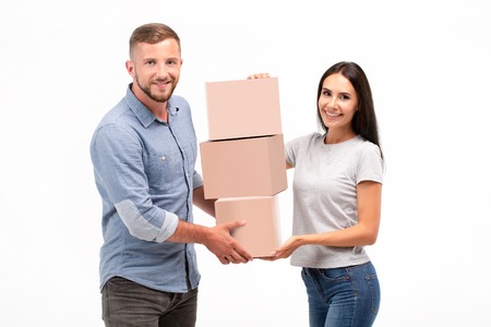 Attractive young couple carrying moving boxes isolated on whiteの写真素材
