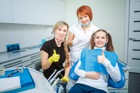 Happy female dentist checking patient teen girl teeth up at dental clinic officeの写真素材