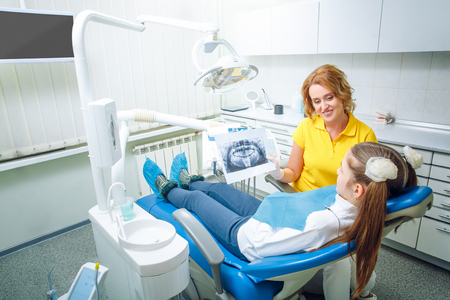 Dentist shows a teen girl patient x-ray of teethの写真素材