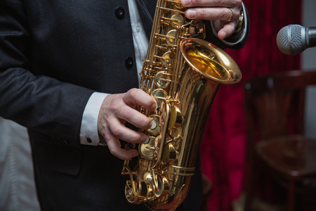 Saxophone player. Saxophonist hands playing saxophone. Alto sax player with jazz music instrument closeupの写真素材