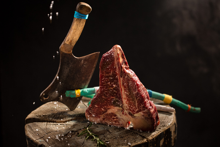 Raw Fresh Marbled Meat Beef ax on a stump on black background.の写真素材