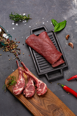 Meat Raw Fresh Mutton on the bone Spices Chesno and Rosemary on a black background. tenderloin. cooking foodの写真素材