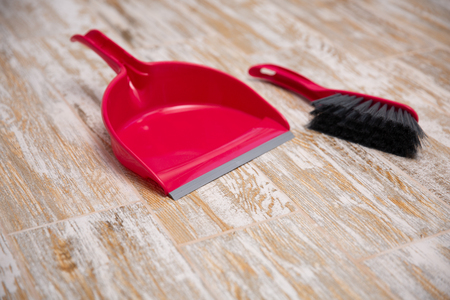 Broom and scoop on wooden background. Plastic equipment for cleaning. red set for sweeping the floorの写真素材