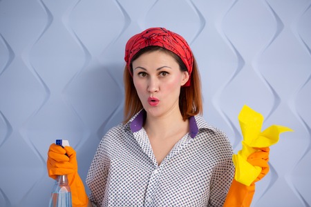 Portrait of woman with cleaning supplies on blue background. housewife with rag and spray tired...