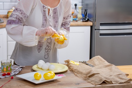 Woman's hands are painting eggs in yellow color on the working surface. Easter egg coloringの写真素材