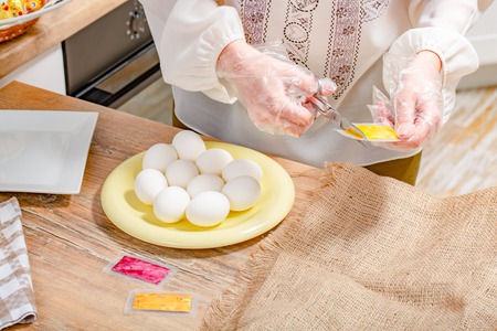 Painting Easter eggs. Method of work of the art of decorating Easter eggs. woman scissor package with dye for eggsの写真素材