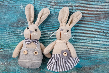 two white rabbits on blue wooden background. couple cute Bunny toys. Easter bunnies decoration. Minimal Easter concept. Trendy creative photo. Copy space.の写真素材